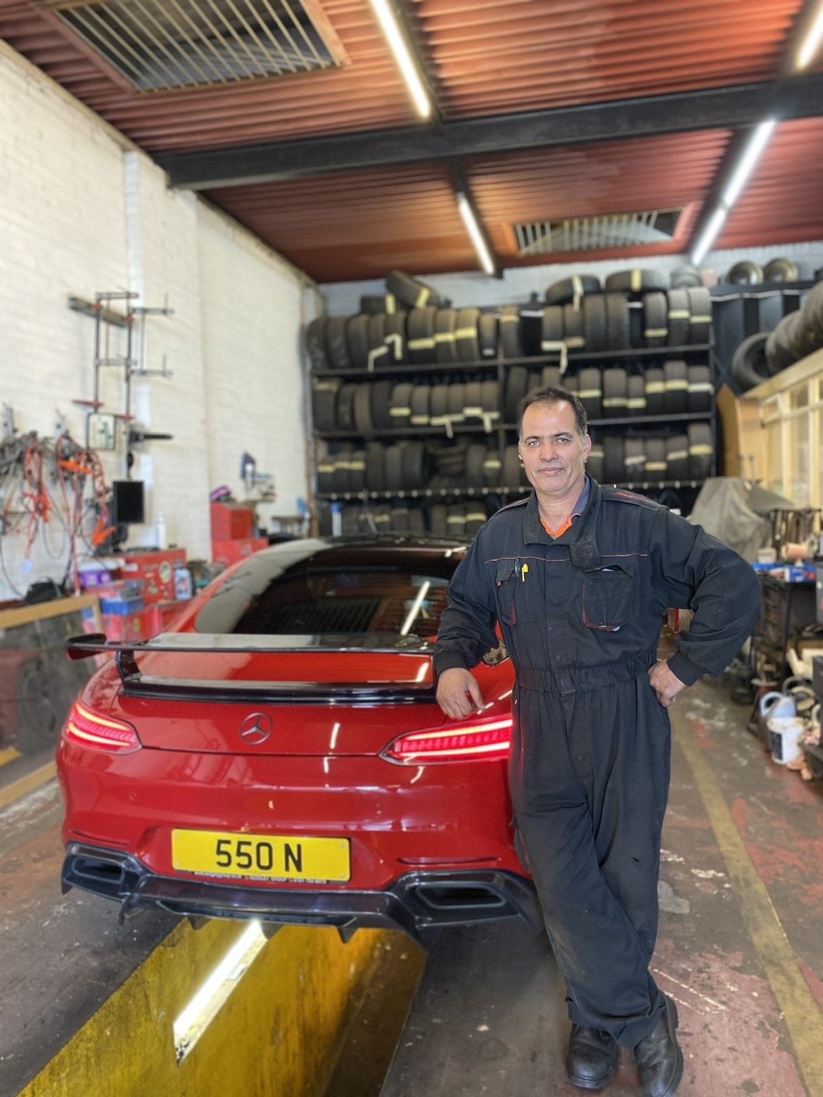 One of the North Street MOT team leaning on a red Mercedes-AMG GT in the workshop